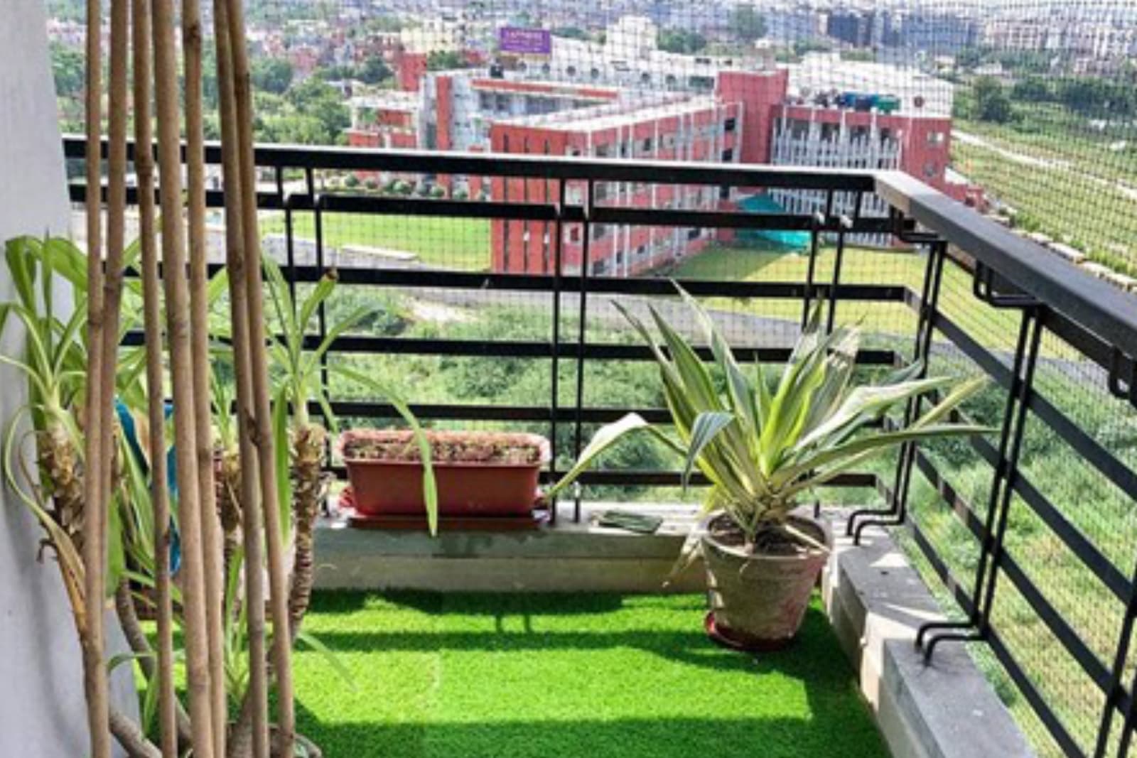 Apartment balcony with potted plants and safety net overlooking a city view
